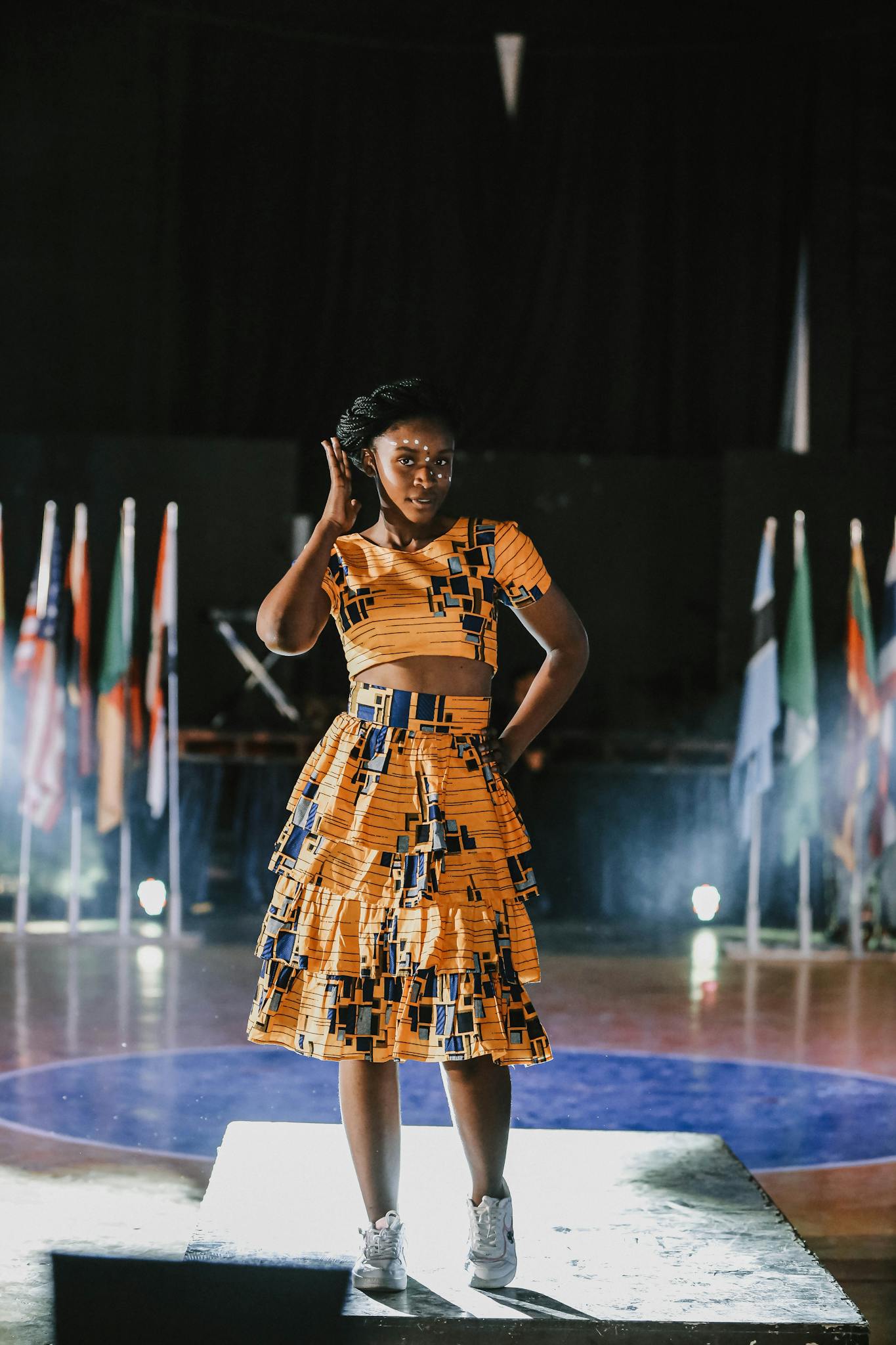 A woman in vibrant traditional attire on a fashion show runway.