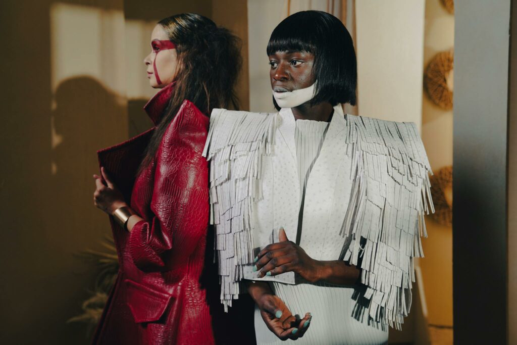 High fashion editorial photo featuring two models in dynamic outfits at a fashion show.