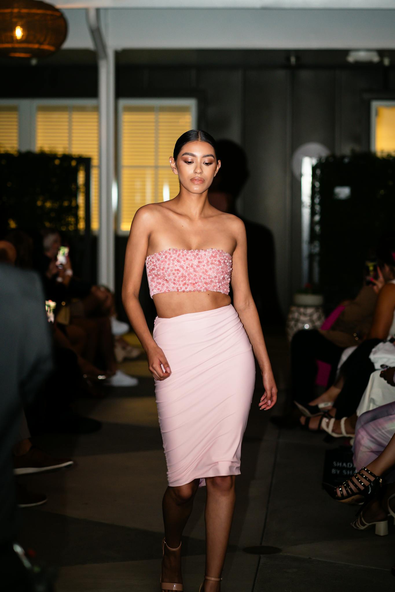 A fashion model walking on the catwalk wearing an elegant evening outfit during a fashion show.