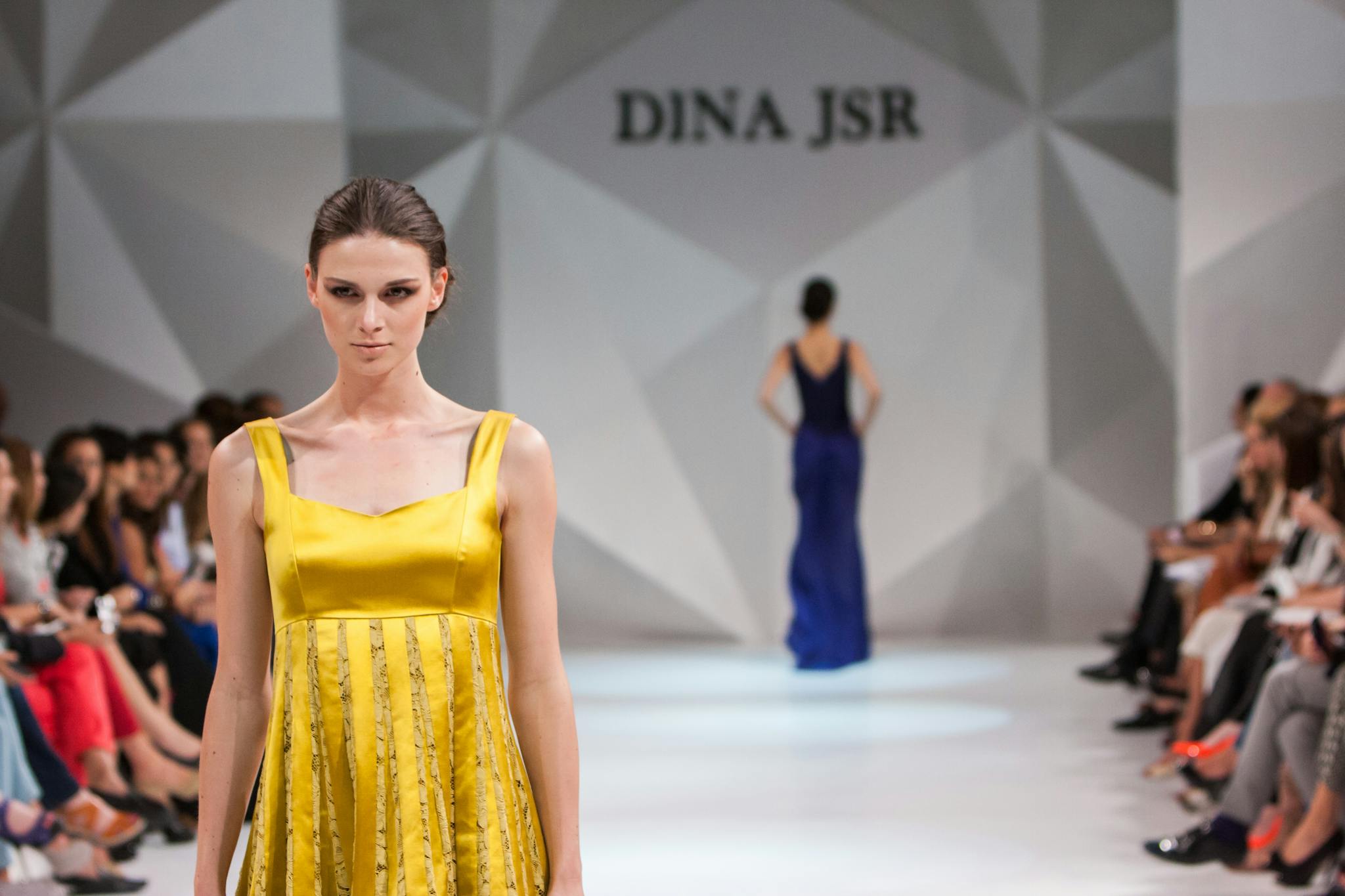 Model showcases a stunning Dina JSR dress during a fashion show runway event.